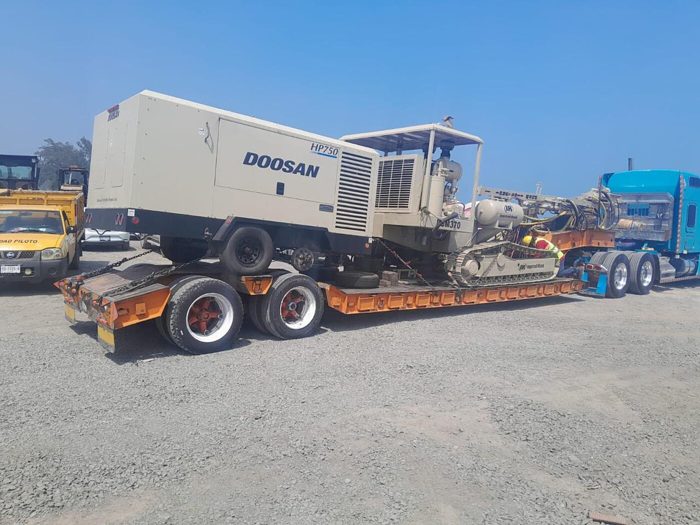 <b>Fierro propio</b> — compresor Doosan HP750 sobre lowboy propio. El equipo no se renta: se mueve.